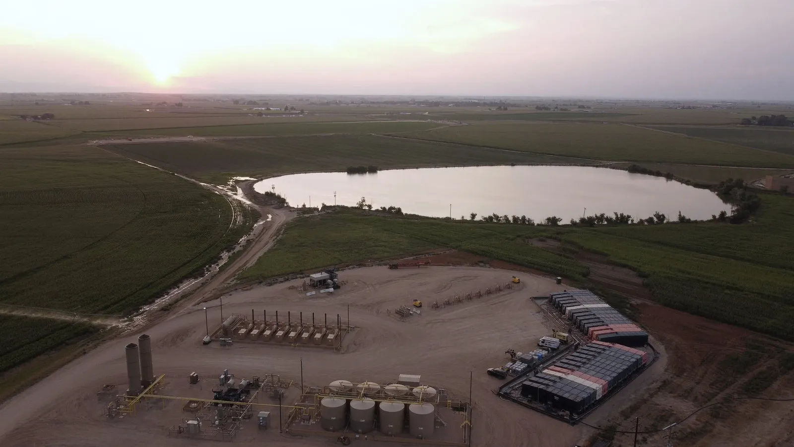 Aerial photograph of a PWR treatment facility: storage tanks, containment and a lined water impoundment set in irrigated farmland.