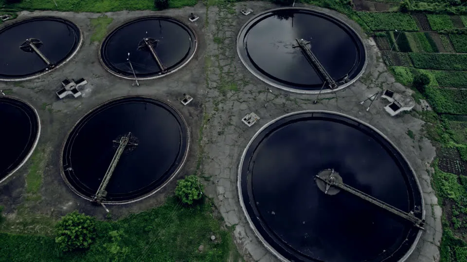 Aerial view of clear clarifier basins beside green farmland: treated water in beneficial reuse