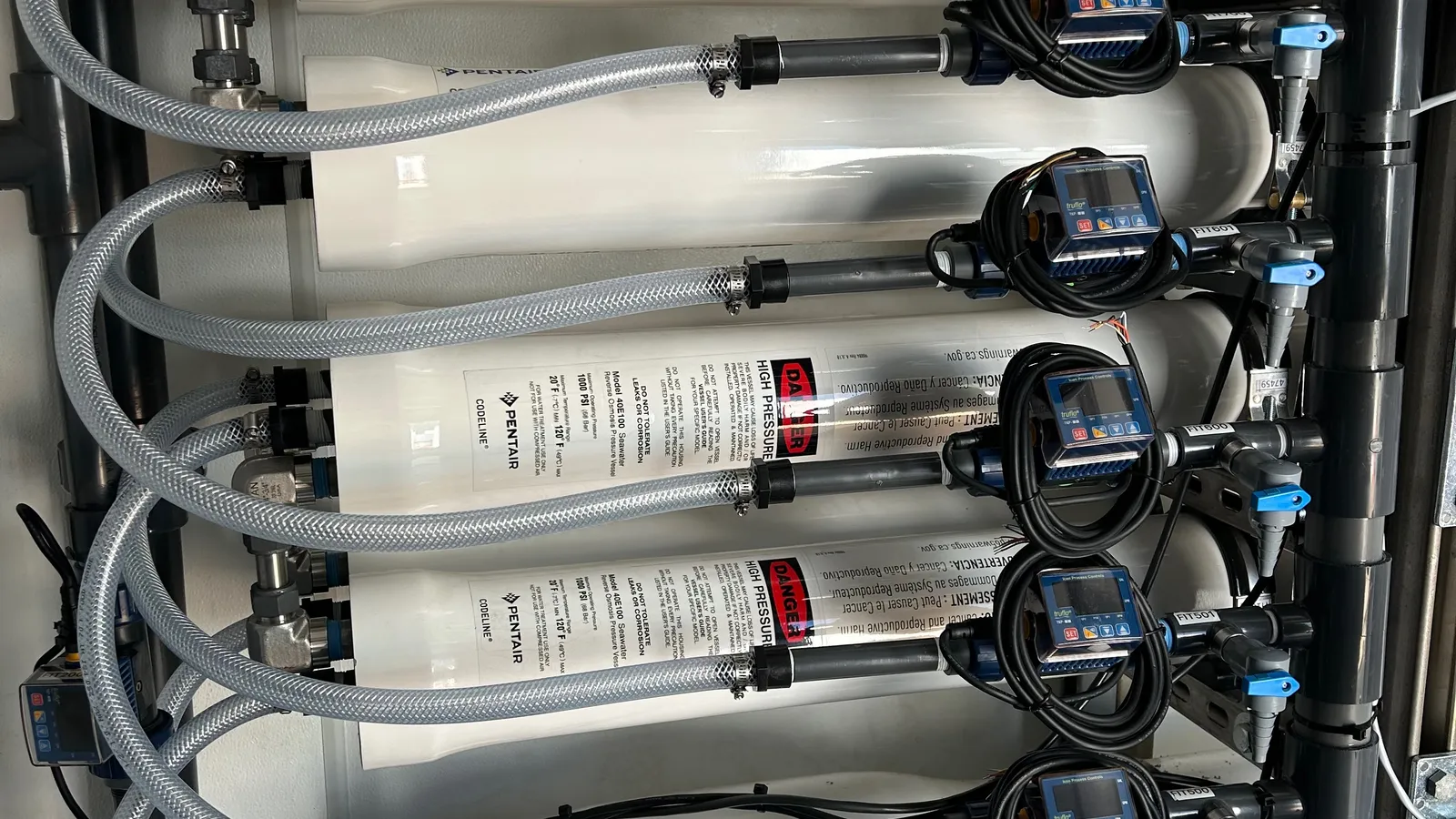 Reverse osmosis pressure vessels stacked inside a PWR treatment skid, each stage with its own pressure transmitter and flow meter.